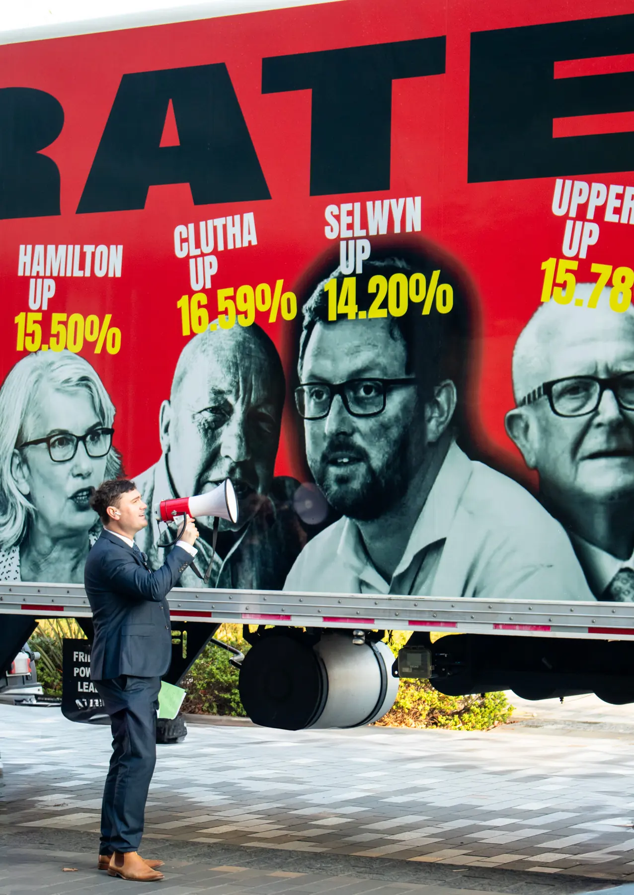 Speaker with megaphone in front of a CAP RATES NOW truck wrap